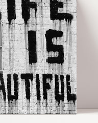After Hover: Banksy - Life is beautiful Frau mit Rose im Haar mit Schriftzug